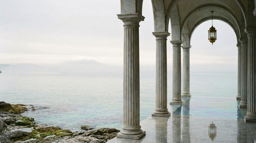 A marble colonnade of classical columns opening onto the Pacific, with a lantern hanging between the arches.